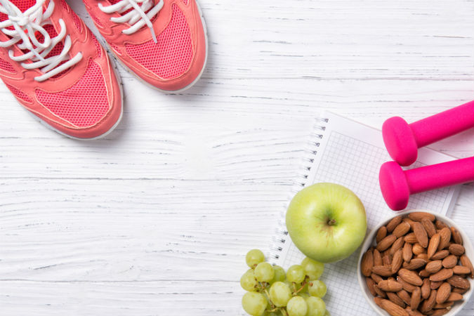 Sportschuhe, Obst, Nüsse und Hanteln liegen auf dem Boden