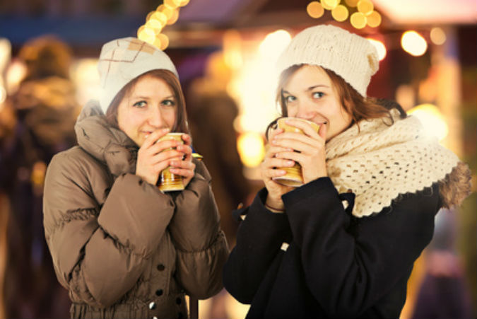 Zwei Frauen stehen mit Glühwein auf einem Fest.