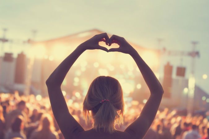 Festivalbesucherin zeigt der Musikbühne ein Herz mit ihren Händen