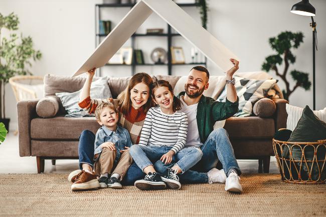 Eine Familie sitzt glücklich im Wohnzimmer ihres Eigenheims