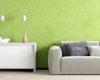 Ein graues Sofa und eine weiße Kommode vor einer grünen Wand.