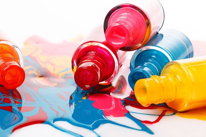 Mehrere bunte, geöffnete Nagellack-Flaschen liegen aufeinander