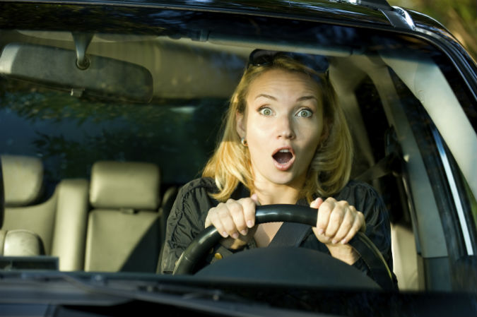 Schockierte Frau beim Auto fahren