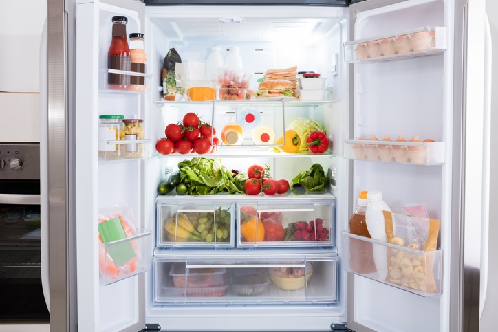 Geöffneter Kühlschrank mit Obst und Gemüse gefüllt.