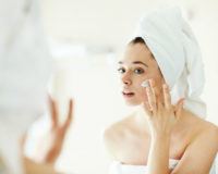 Frau trägt nach dem Duschen Feuchtigkeitscreme im Gesicht auf