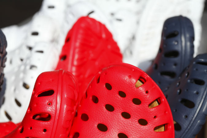 Die Spitzen von vielen Crocs in rot, schwarz und weiß