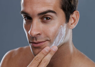 Studio shot of a handsome young man applying cream to his face
