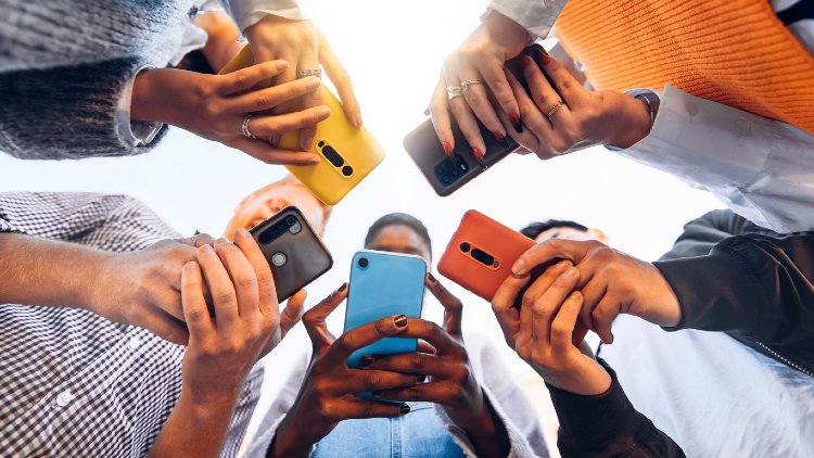 Fünf Personen stehen mit ihren Smartphones in einem Kreis zusammen