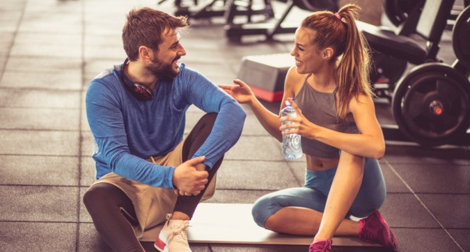 Frau spricht Mann im Fitnessstudio an