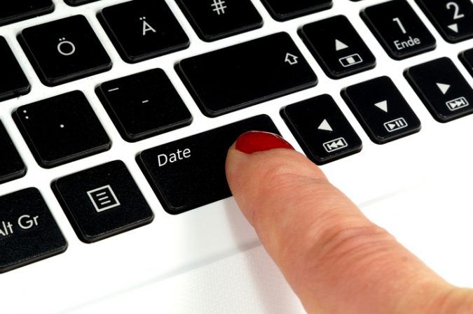 Eine Frau drueckt auf die "Date-Taste" ihres Notebooks