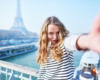 Junge Frau macht ein Selfie mit dem Eiffelturm im Hintergrund