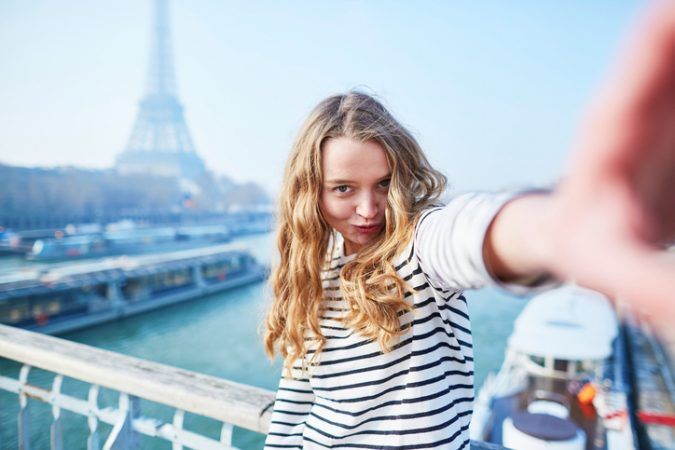 Junge Frau macht ein Selfie mit dem Eiffelturm im Hintergrund