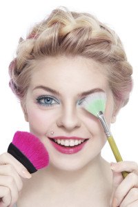 Blonde Frau mit Make-Up Utensilien